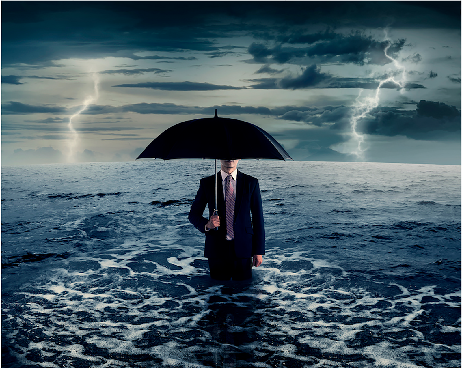 man holding umbrella while standing in stormy ocean