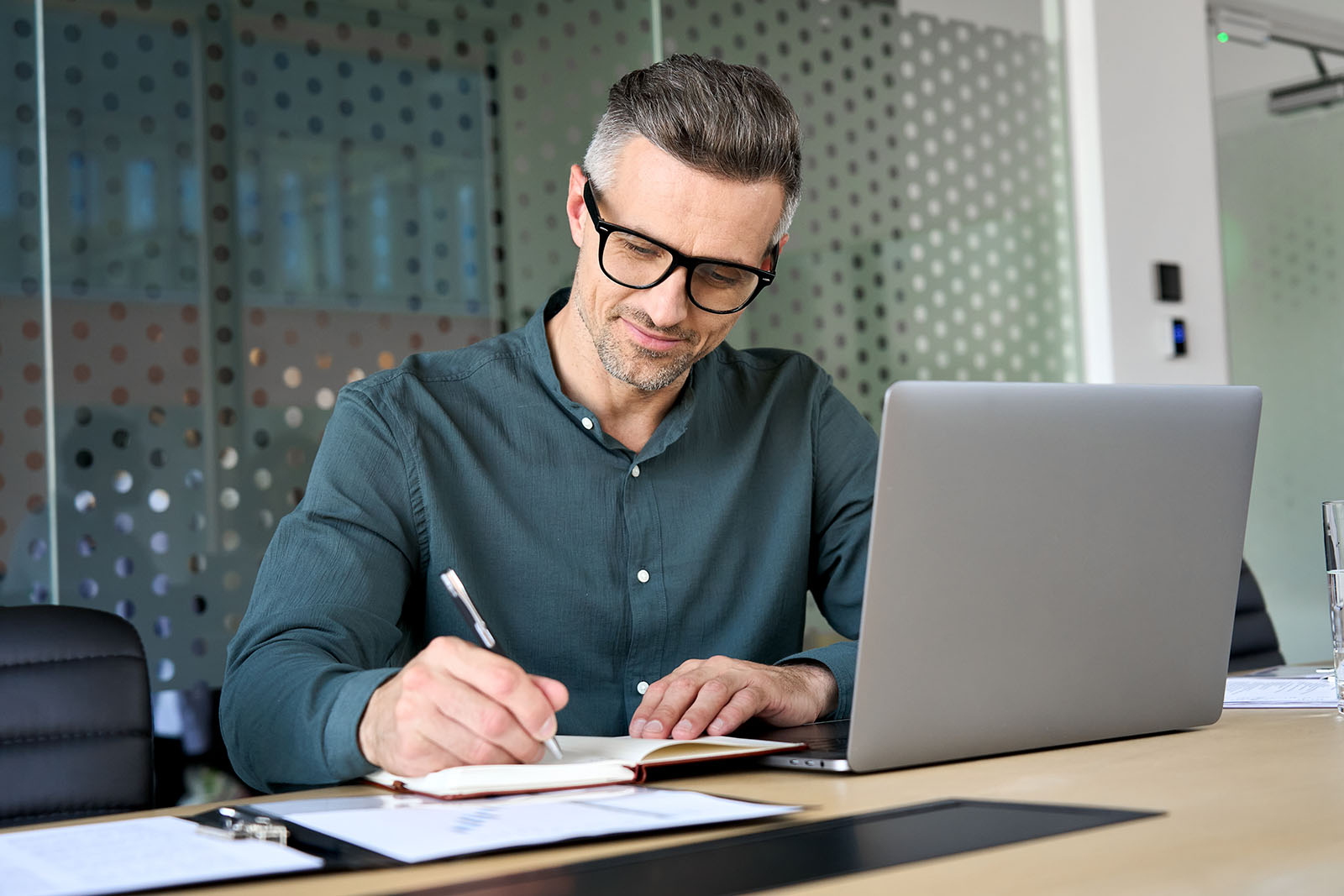man in office writing notes at desk